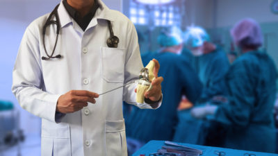 Orthopedic doctor showing model of Total knee replacement with b